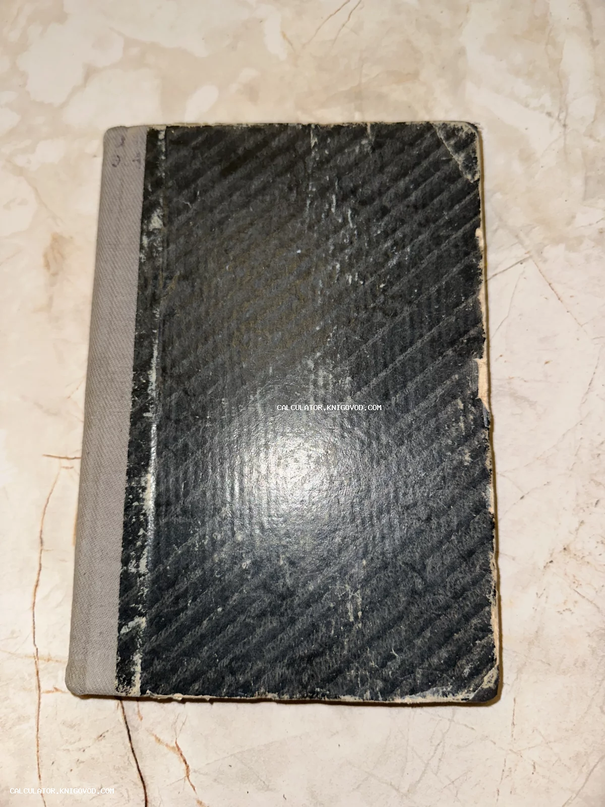 Старинная книга или тетрадь с черной фактурной обложкой и серым корешком на светлом фоне