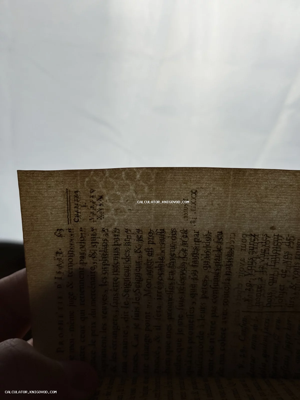 Старинная пожелтевшая страница с текстом «PROPHETIE D'ISAIE», сфотографированная на просвет.