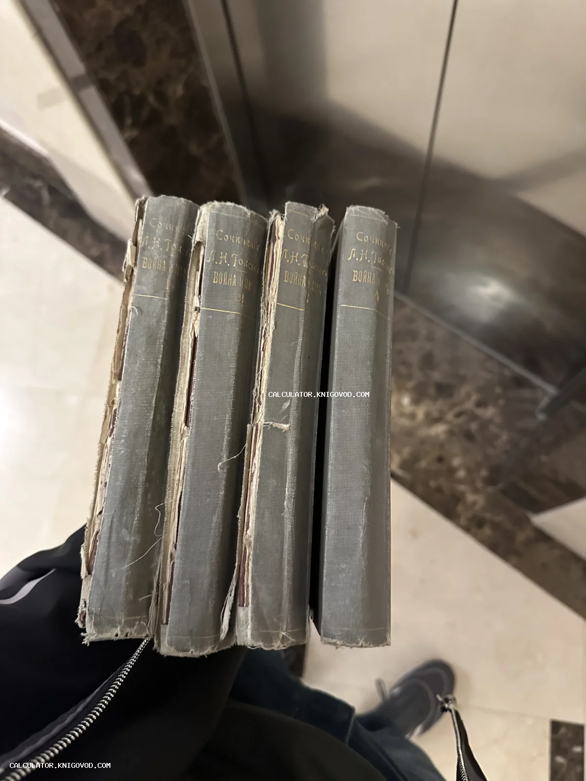 Четыре старинных тома сочинений Льва Толстого «Война и мир» в серых тканевых переплетах с золотым тиснением.
