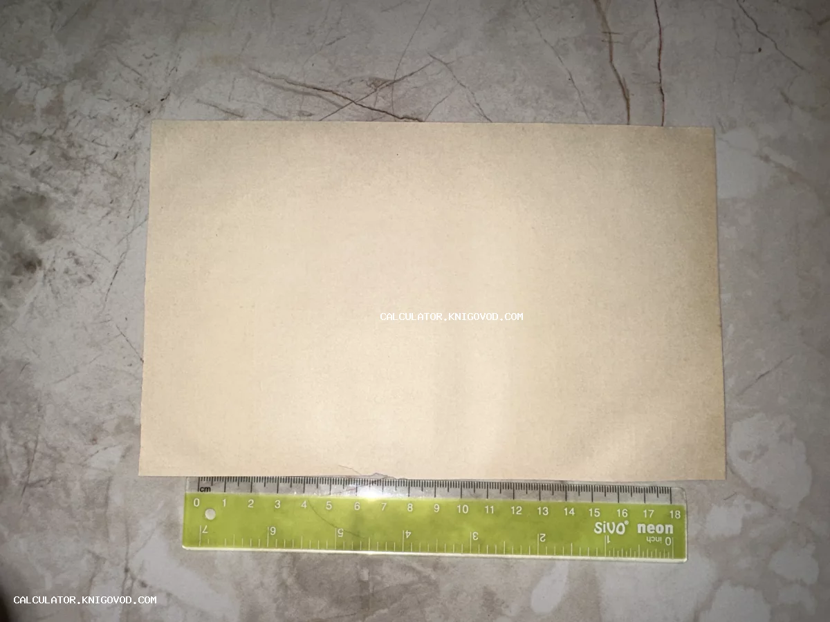 Прямоугольный лист старой пожелтевшей бумаги рядом с измерительной линейкой на мраморном фоне.