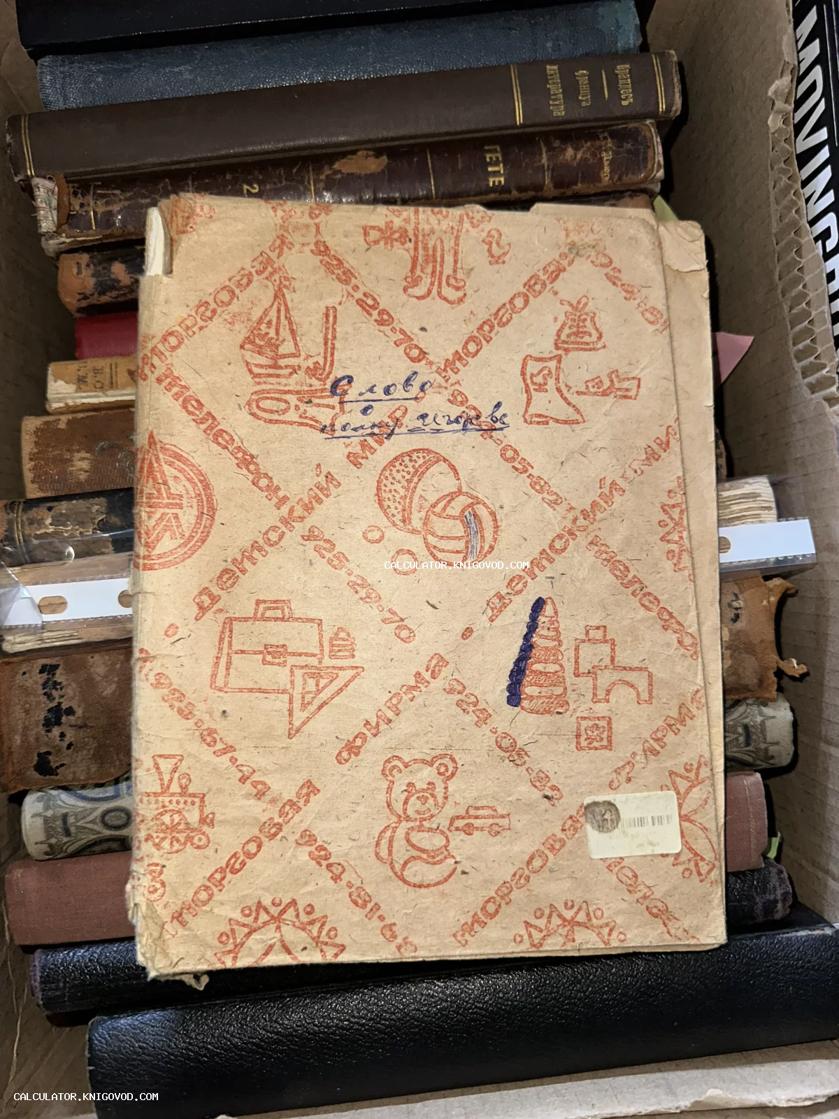 Стопка антикварных книг в коробке, на переднем плане книга в бумажной обертке с красными принтами магазина Детский мир и надписью Слово о полку Игореве.