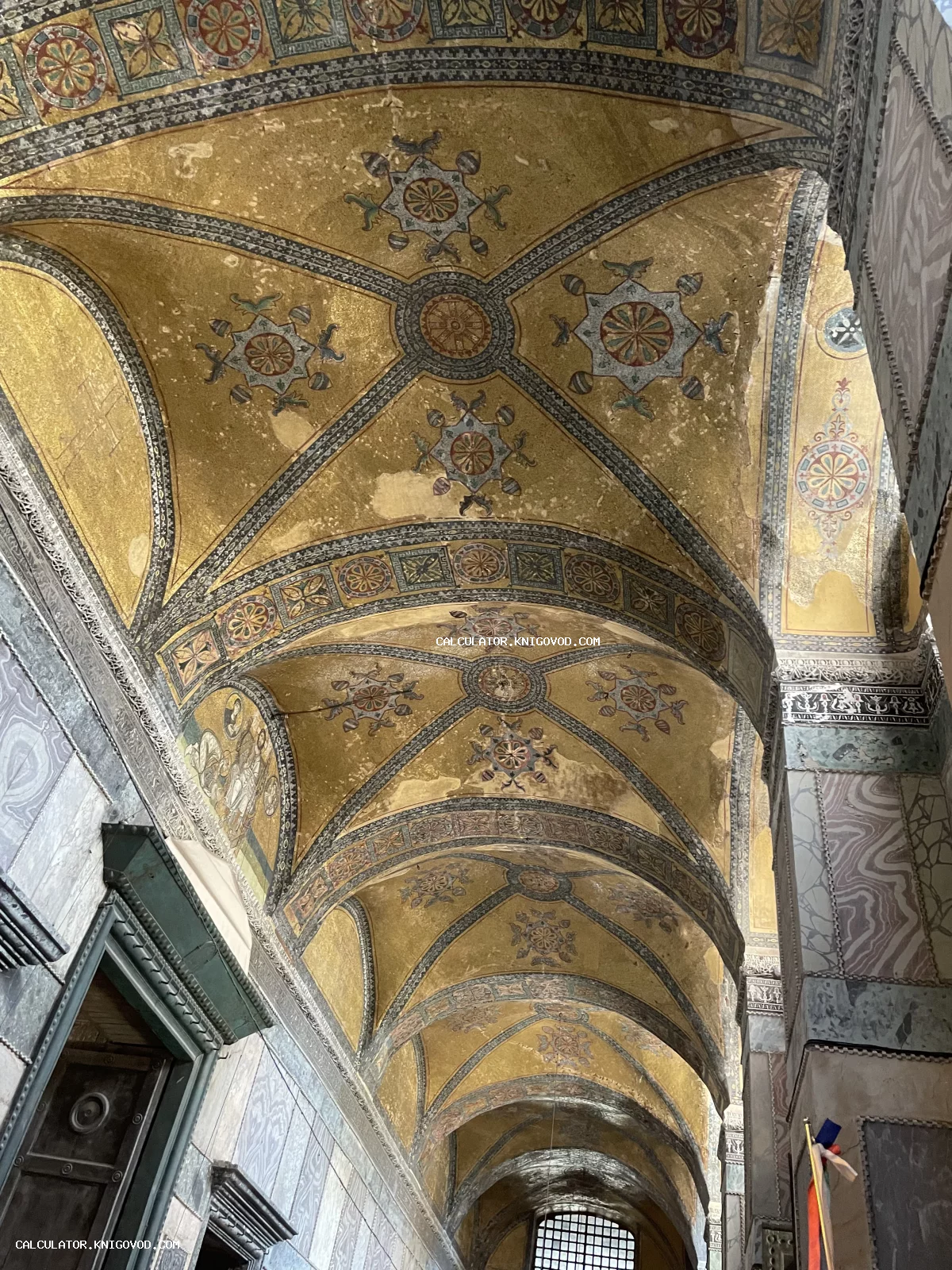 Вид на аркаду и сводчатый потолок с золотой византийской мозаикой и геометрическими орнаментами.