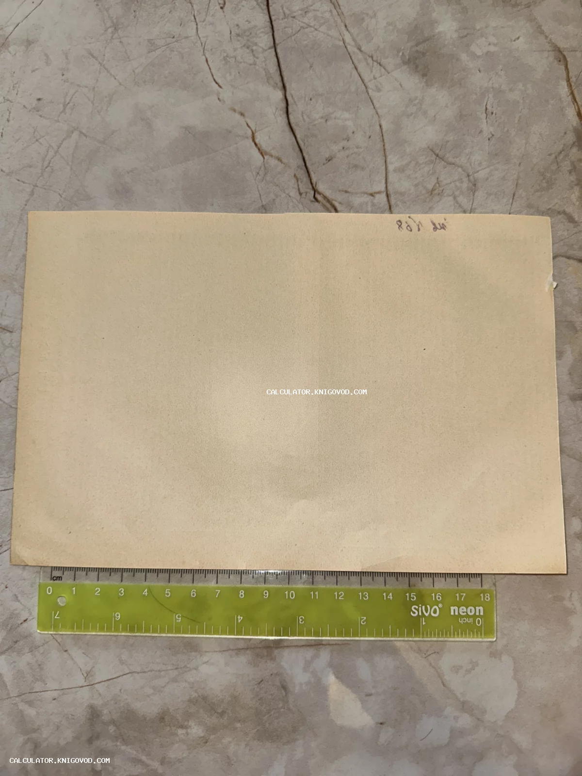 Оборотная сторона пожелтевшей от времени старинной открытки с рукописной пометкой и измерительной линейкой.