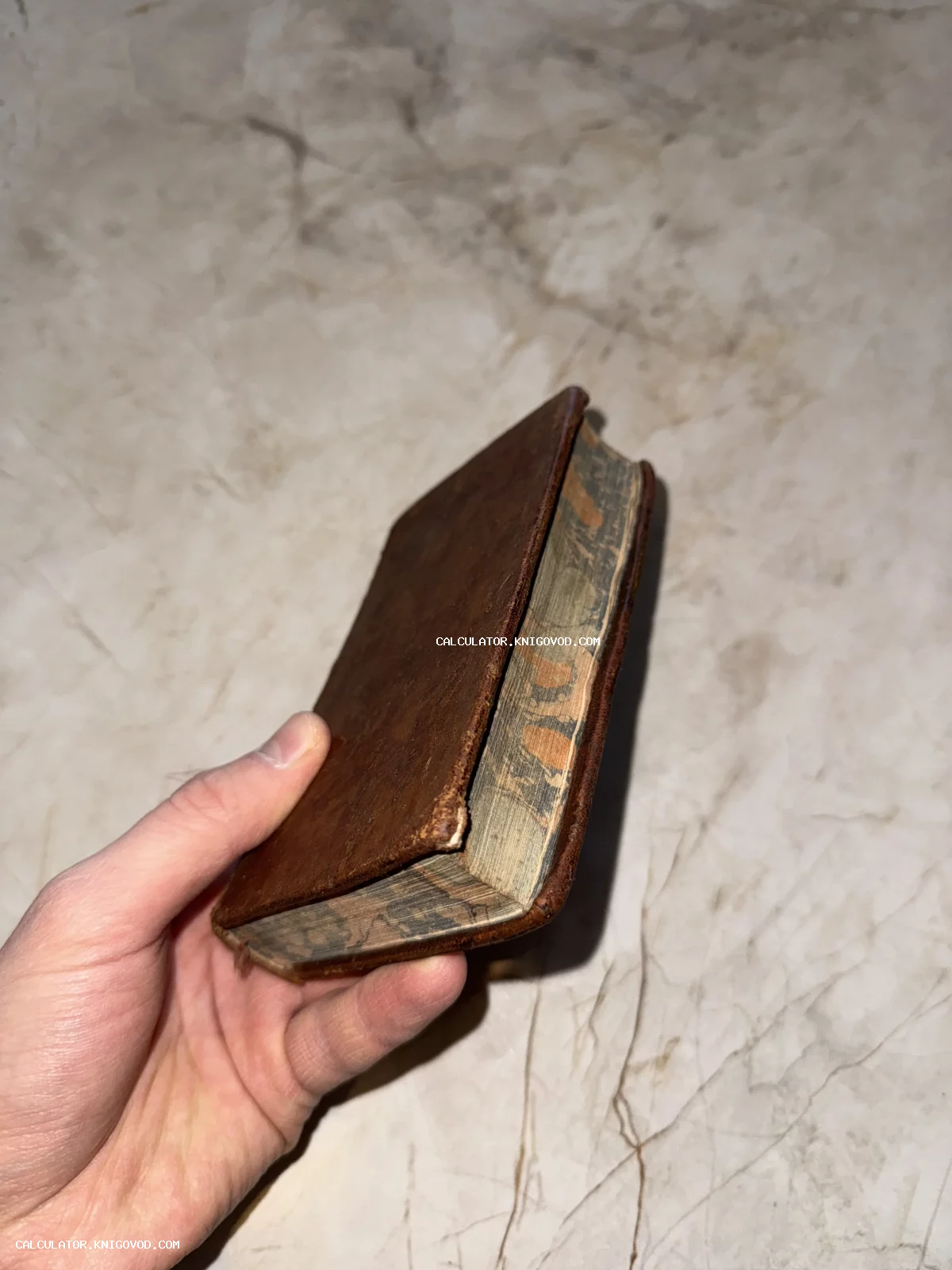 Антикварный карманный томик в потертом коричневом кожаном переплете с мраморным обрезом страниц.