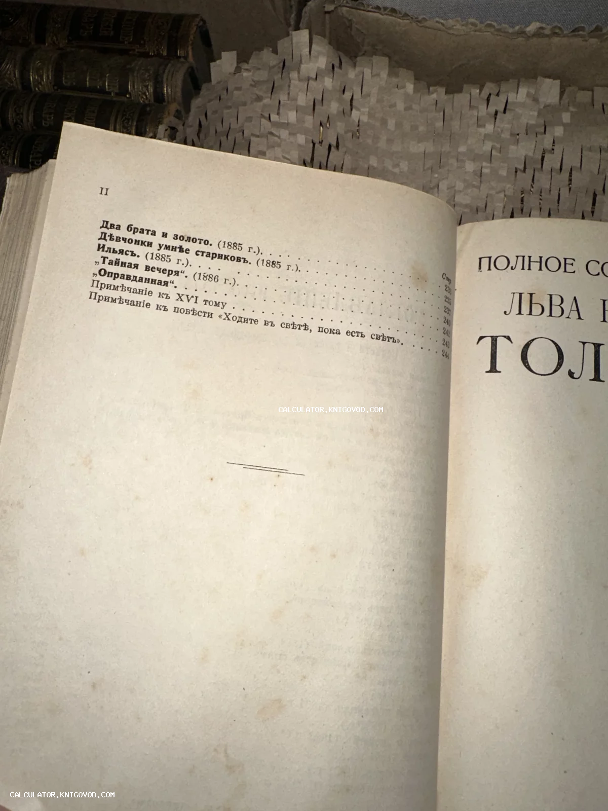 Разворот старинной книги со списком произведений Льва Толстого в дореволюционной орфографии на фоне антикварных корешков.