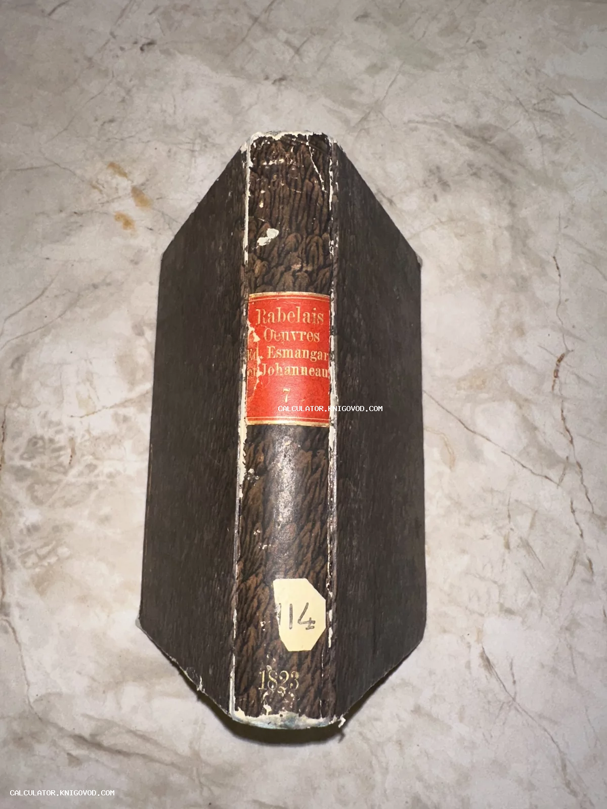 Корешок антикварной книги Франсуа Рабле 'Oeuvres' 1823 года с красной этикеткой на мраморном фоне.