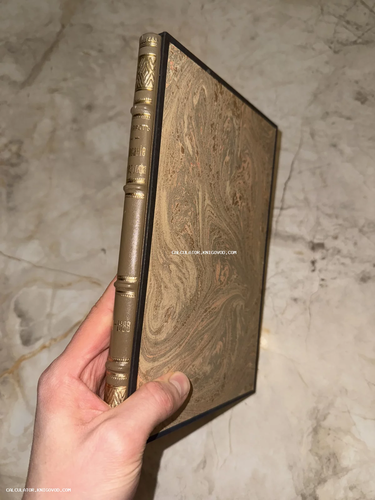 Старинная книга в полукожаном переплете с мраморной бумагой на крышках и золотым тиснением на корешке.