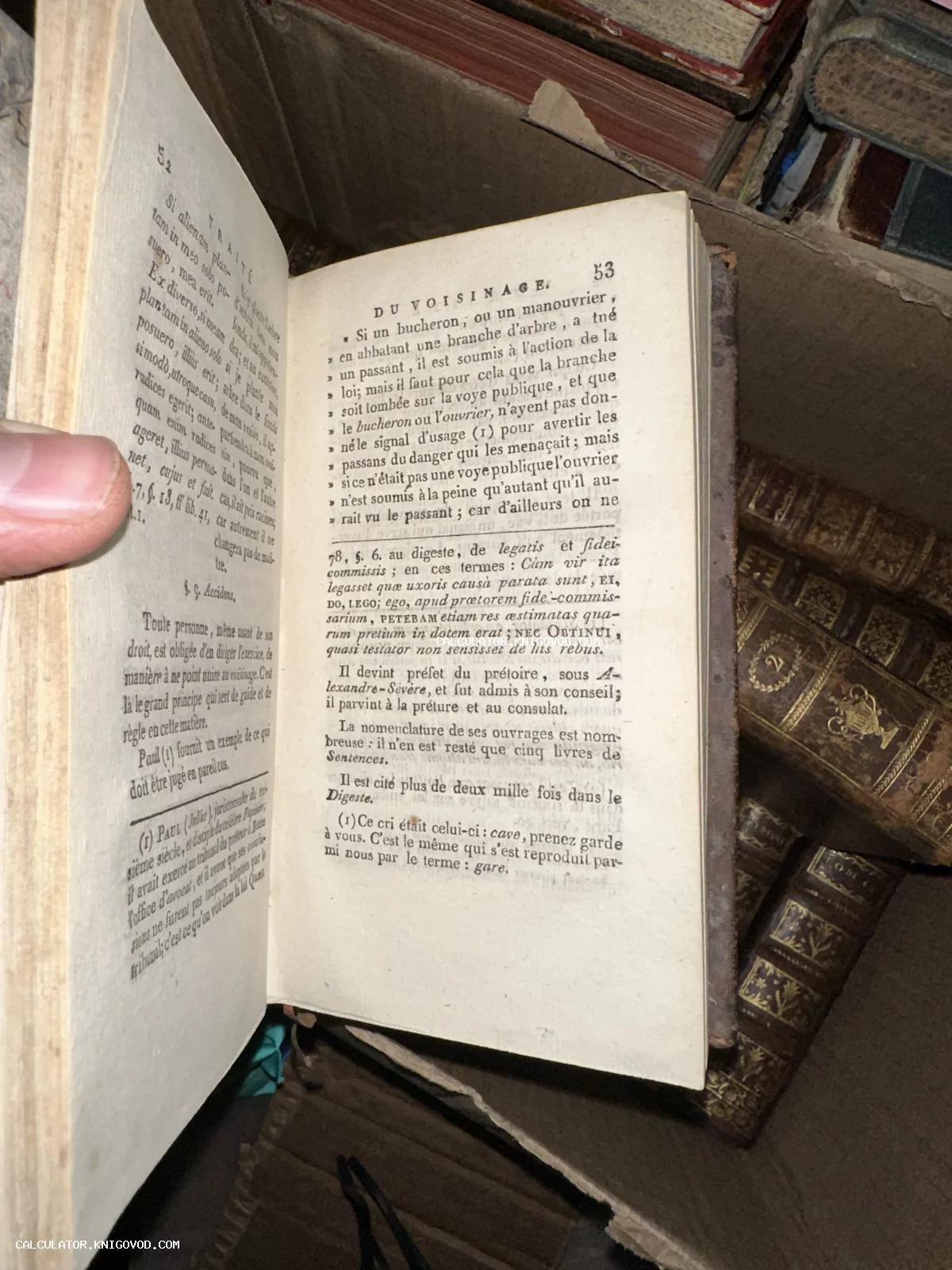 Разворот антикварной книги на французском языке с типографским текстом на фоне старых кожаных переплетов.