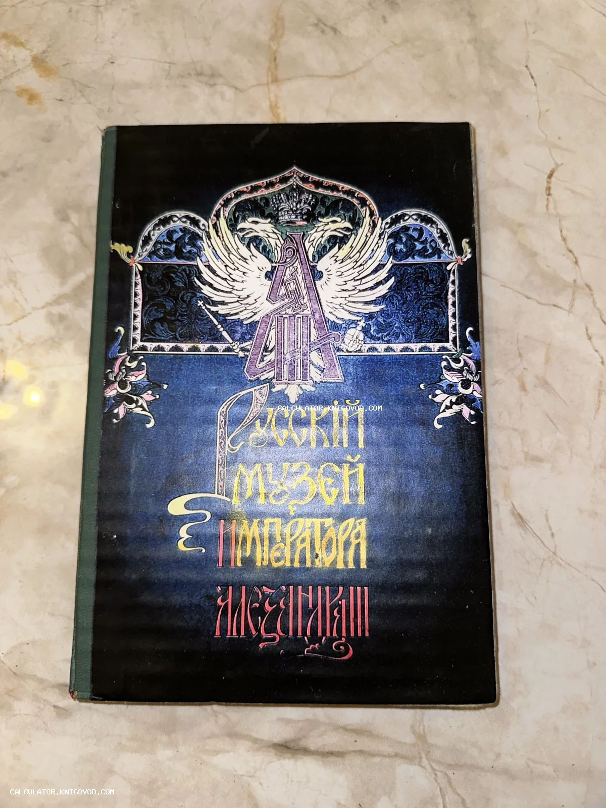 Обложка старинной книги темно-синего цвета с изображением двуглавого орла и стилизованной надписью на старославянском языке.