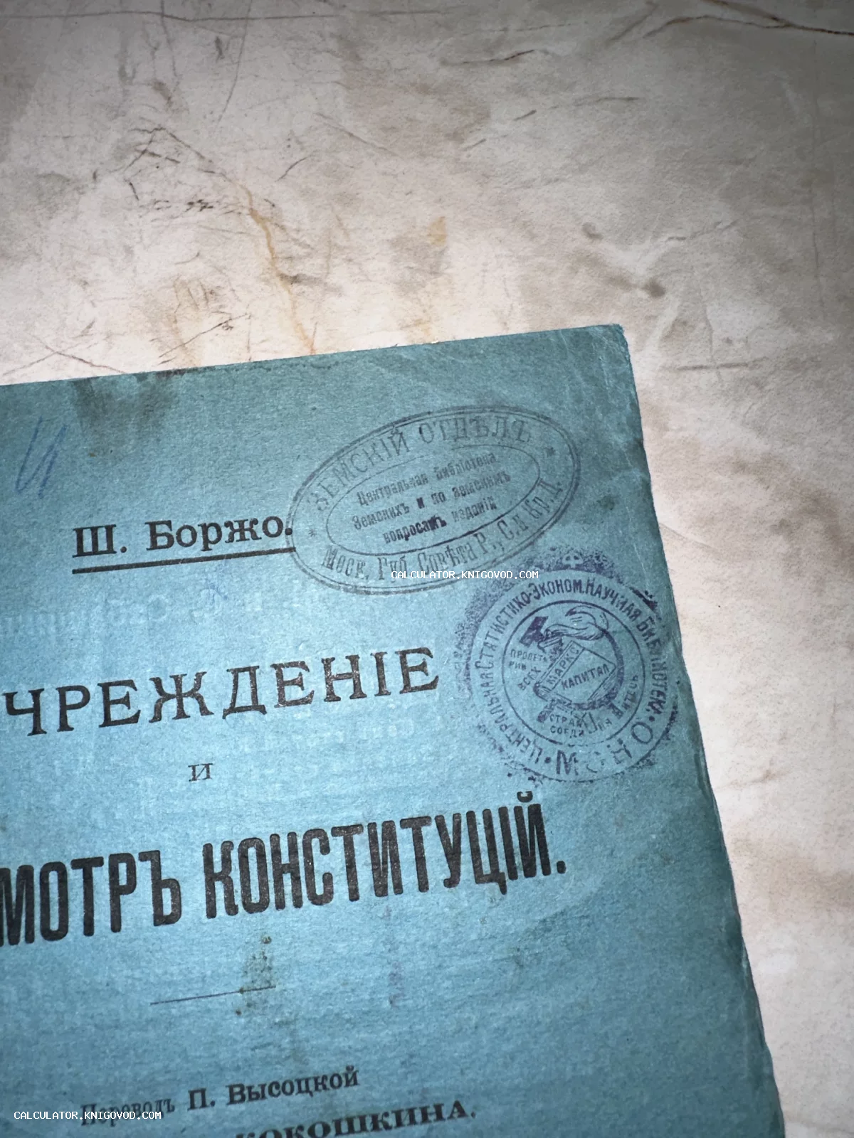 Фрагмент обложки старинной книги голубого цвета с типографским текстом на русском языке и оригинальными библиотечными штампами Земского отдела.