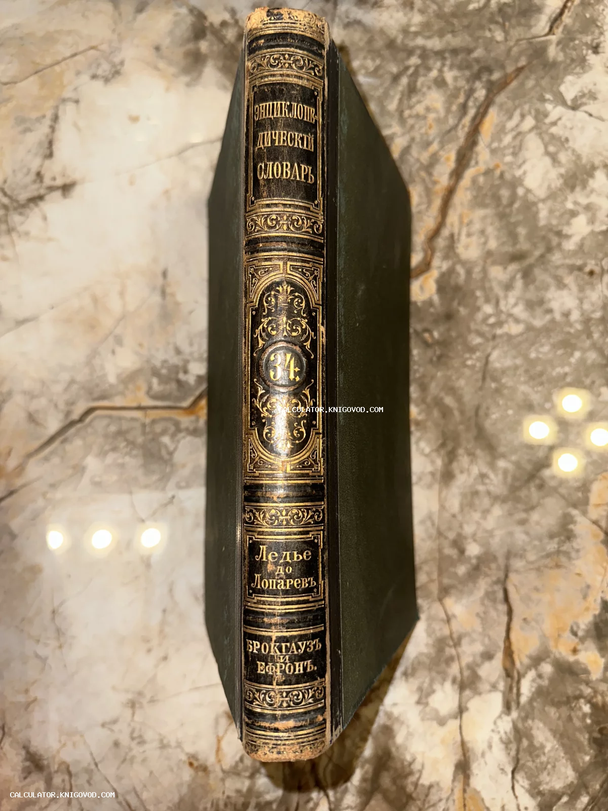 Корешок антикварной книги Энциклопедический словарь Брокгауза и Ефрона с золотым тиснением на мраморной поверхности.