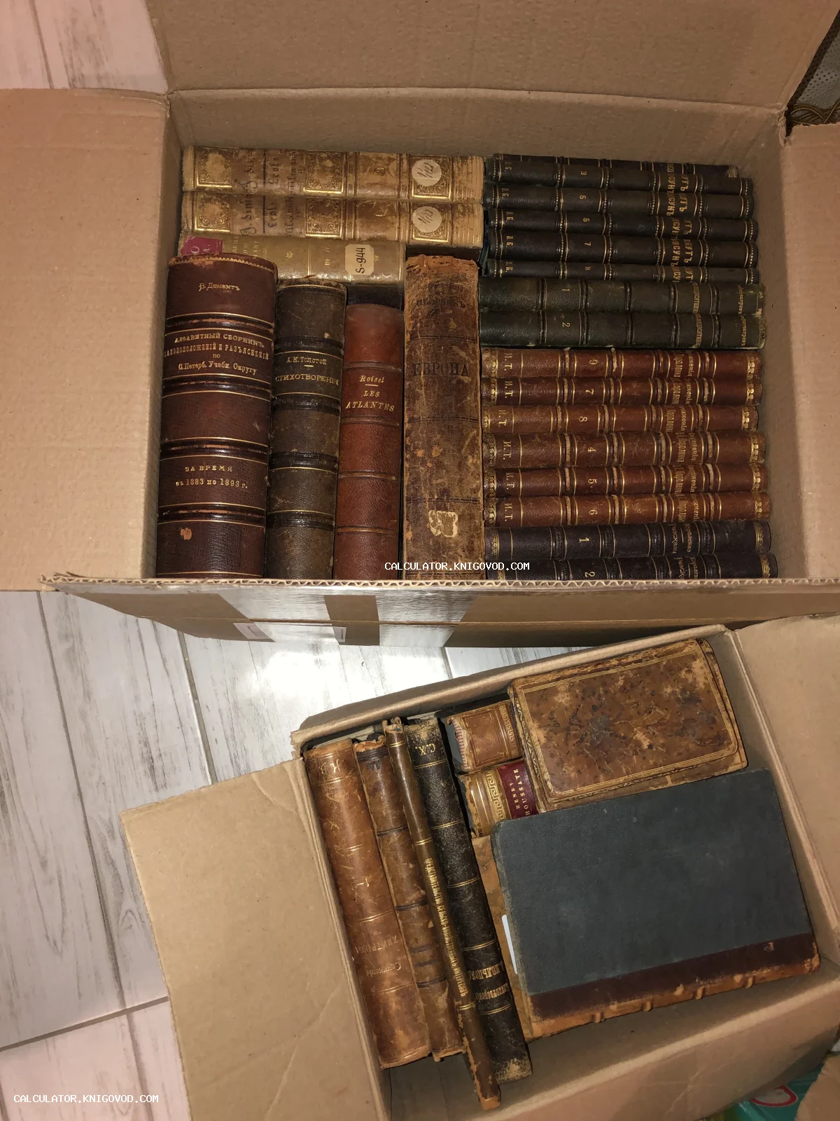Две открытые картонные коробки, плотно заполненные старинными книгами XVIII–XIX веков с золотым тиснением на корешках.