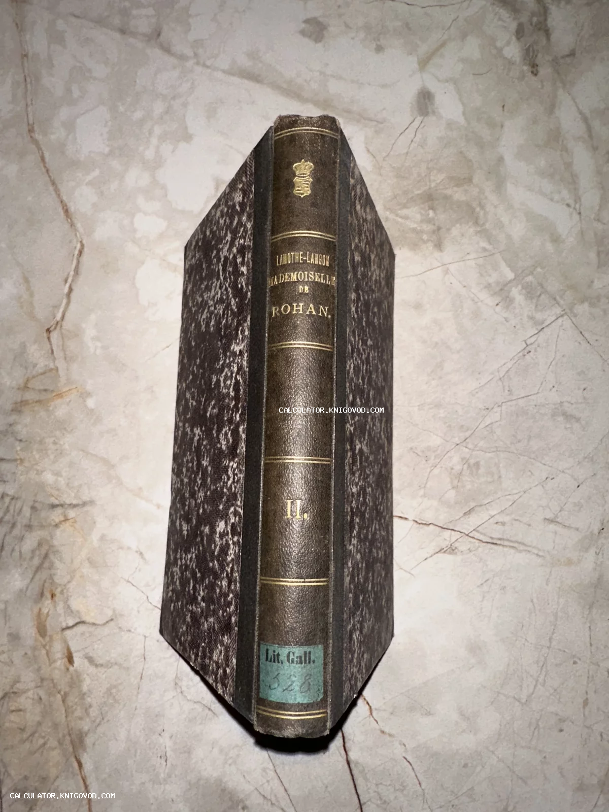 Корешок старинной книги в полукожаном переплете с золотым тиснением и мраморной бумагой на обложке.