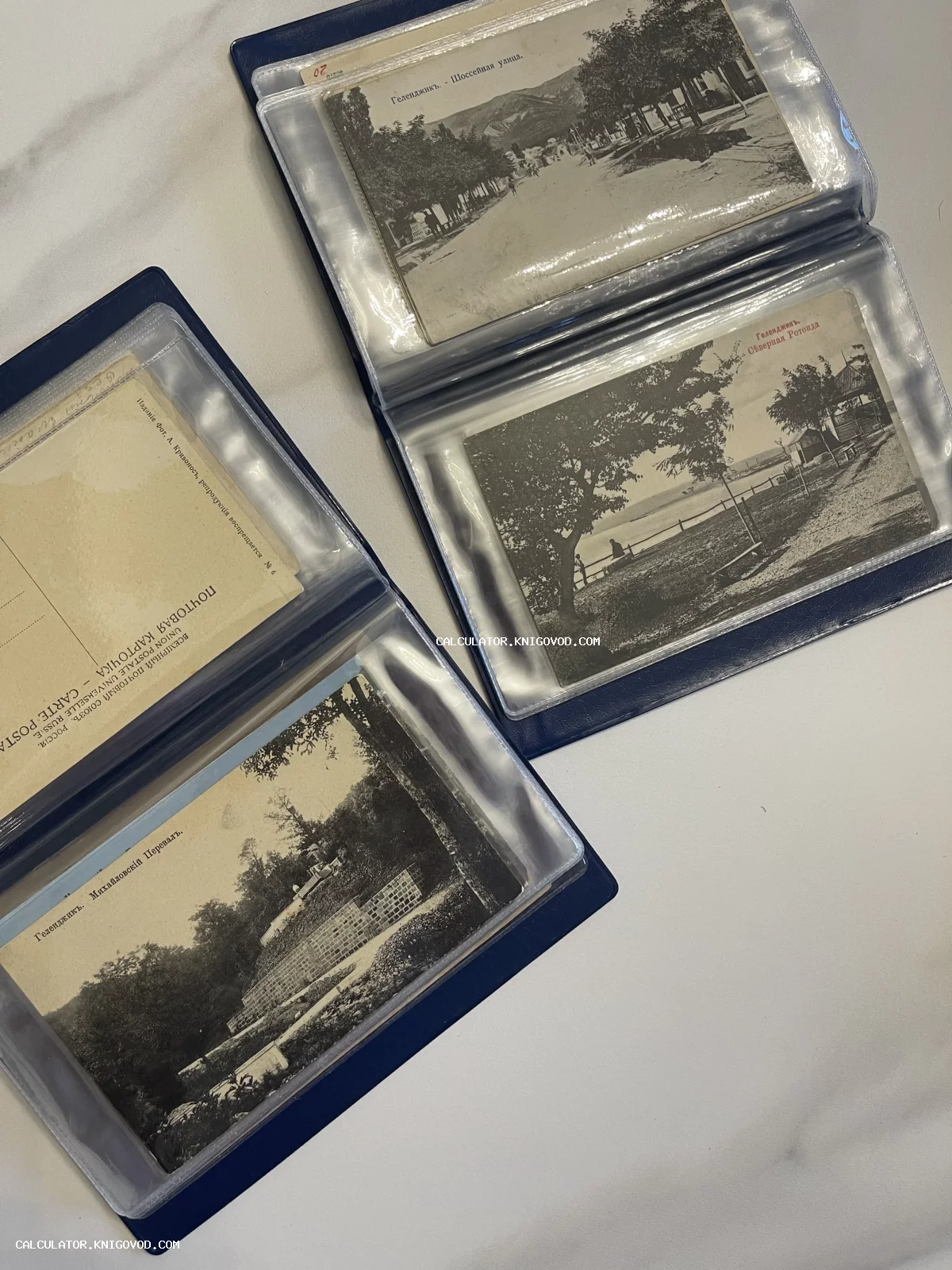 Старинные черно-белые почтовые открытки Российской империи с видами Геленджика, размещенные в коллекционном альбоме.