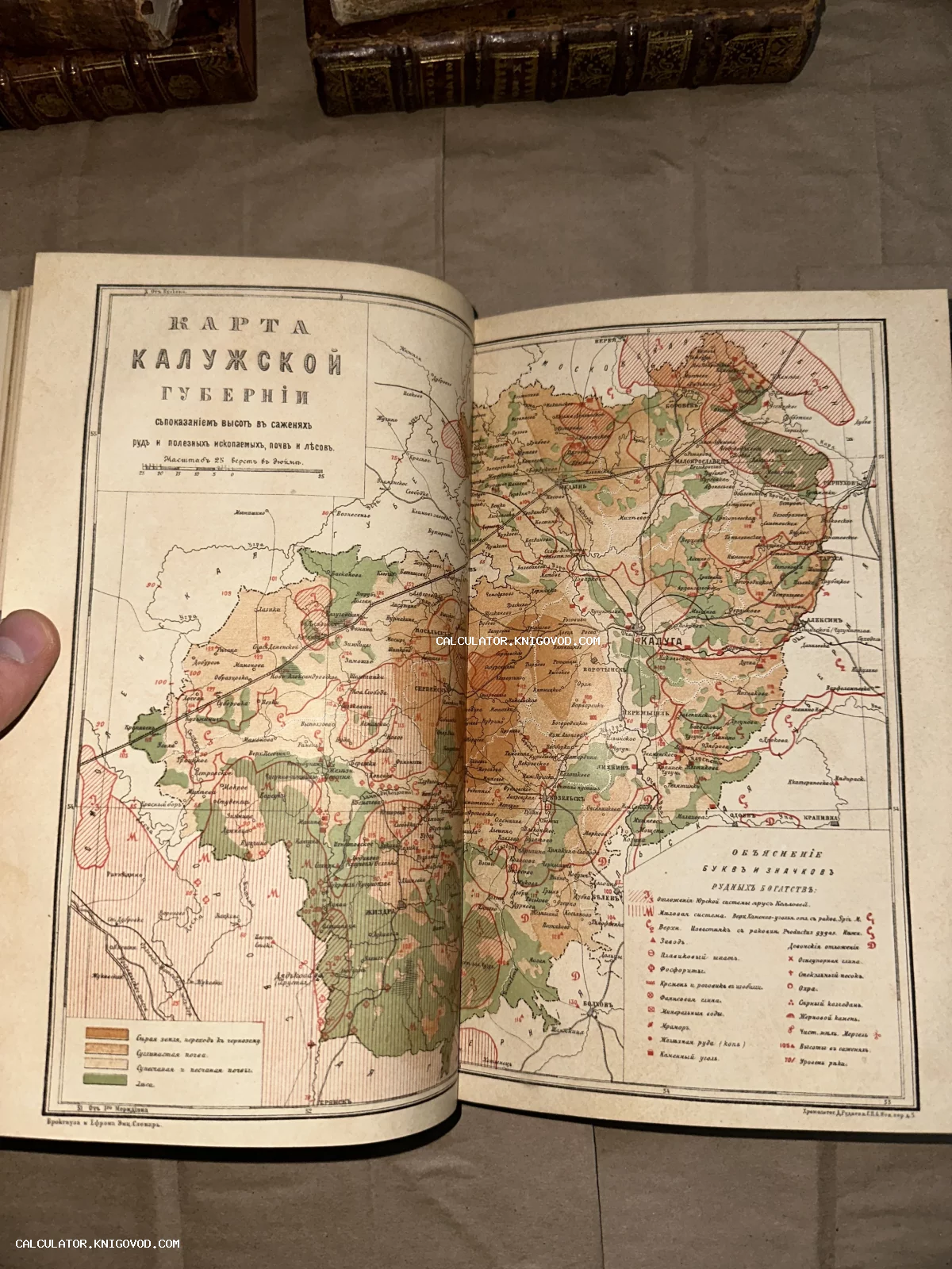 Разворот старинной книги с цветной литографированной картой Калужской губернии и легендой условных обозначений.