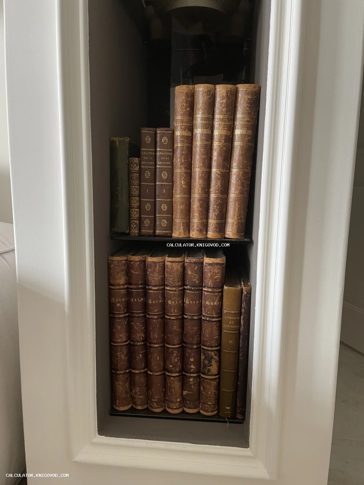 Старинные книги с золотым тиснением на полках в белой стенной нише