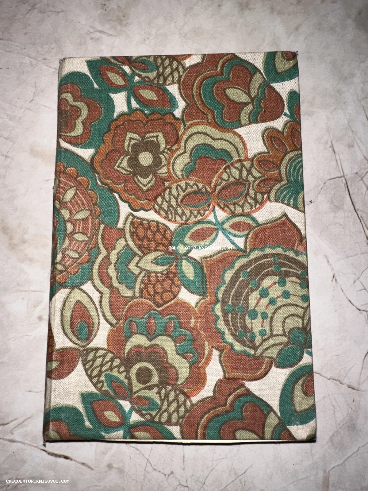 Обложка книги с крупным цветочным орнаментом в ретро-стиле на светлой поверхности.