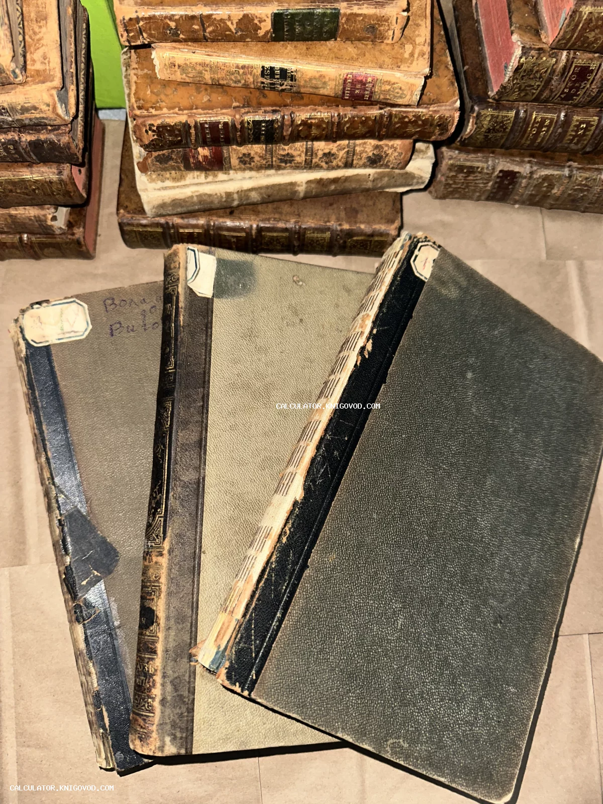 Стопки антикварных книг с изношенными кожаными и тканевыми переплетами, вид сверху.