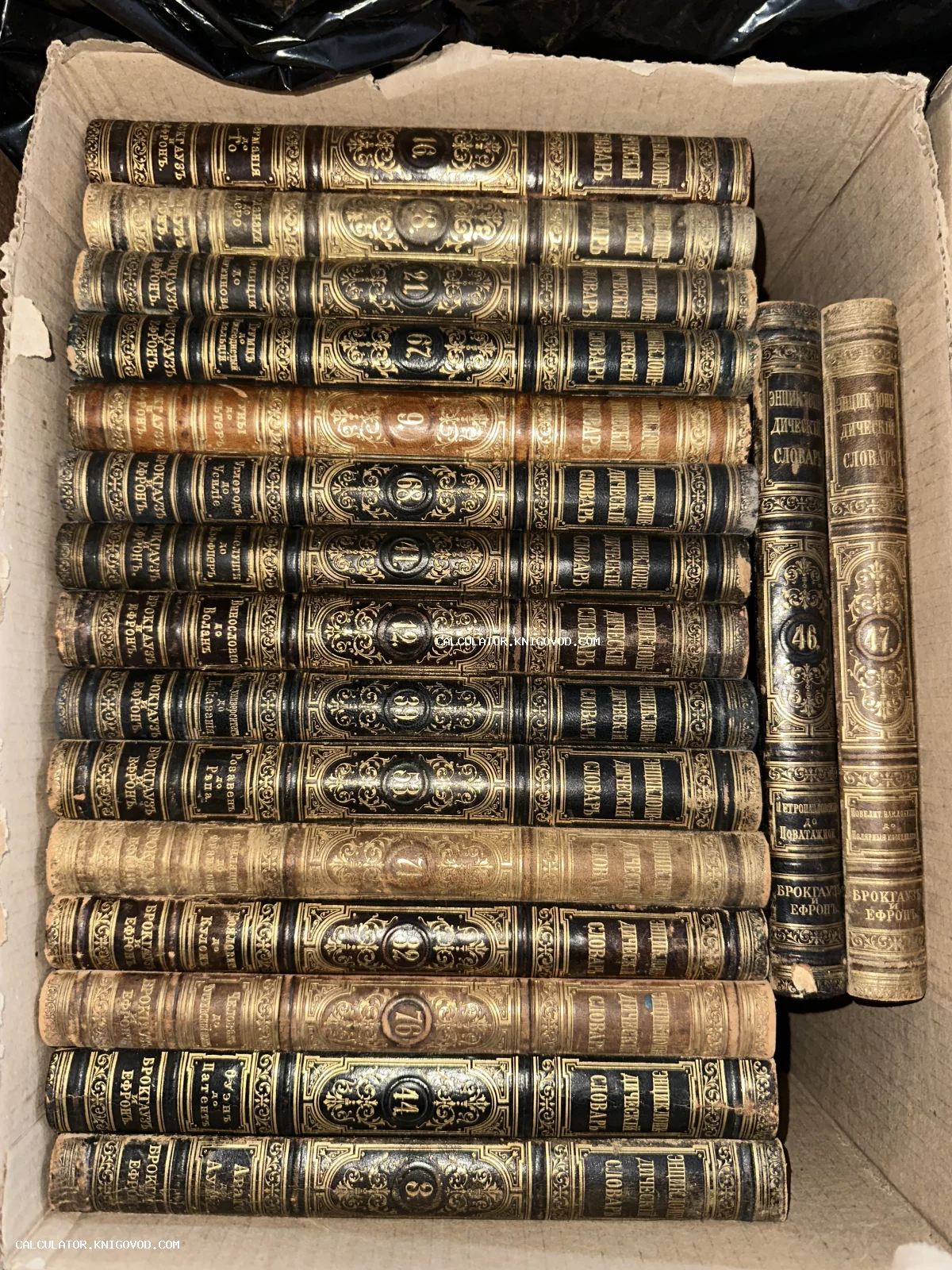 Ряд антикварных книг с золотым тиснением на корешках в картонной коробке. Энциклопедический словарь Брокгауза и Ефрона.