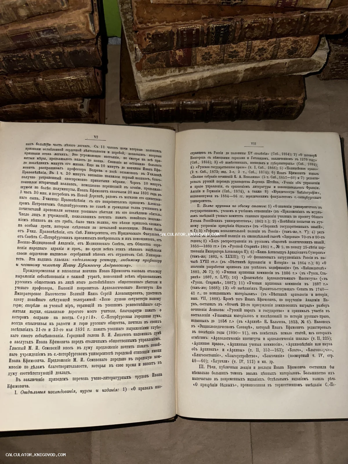 Разворот антикварной книги с текстом на дореволюционном русском языке на фоне стопки старинных томов в кожаных переплетах.