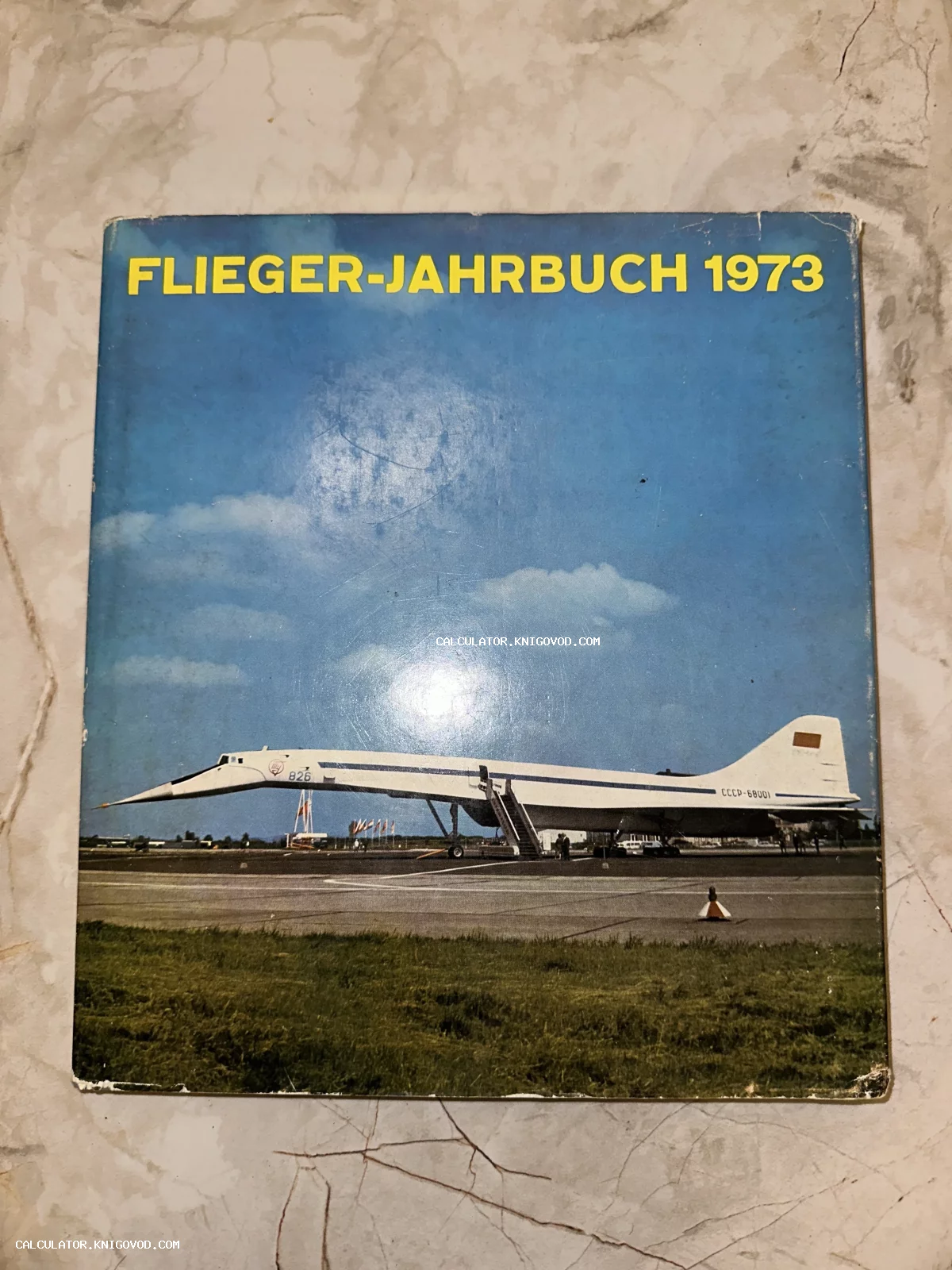 Обложка винтажной книги Flieger-Jahrbuch 1973 с изображением советского сверхзвукового самолета Ту-144 на аэродроме.