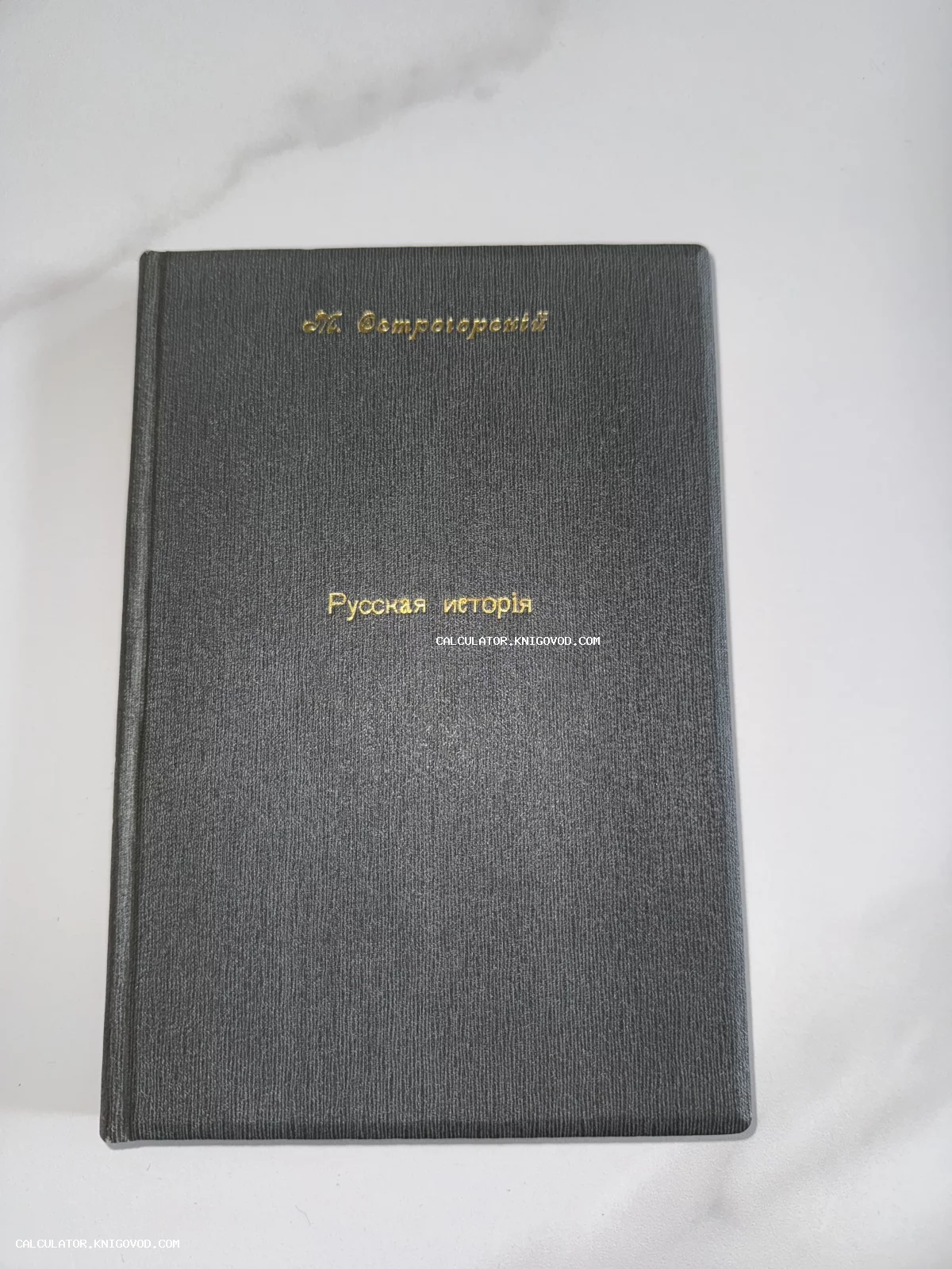 Книга в темно-сером твердом переплете с золотым тиснением «М. Острогорскій. Русская исторія» на светлом фоне.