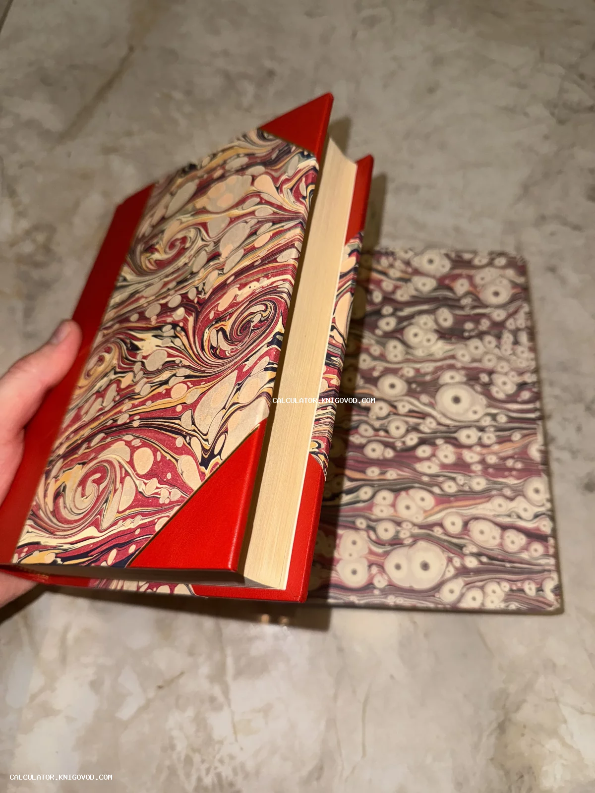 Две книги с обложками из цветной мраморной бумаги и красными кожаными уголками на светлом фоне