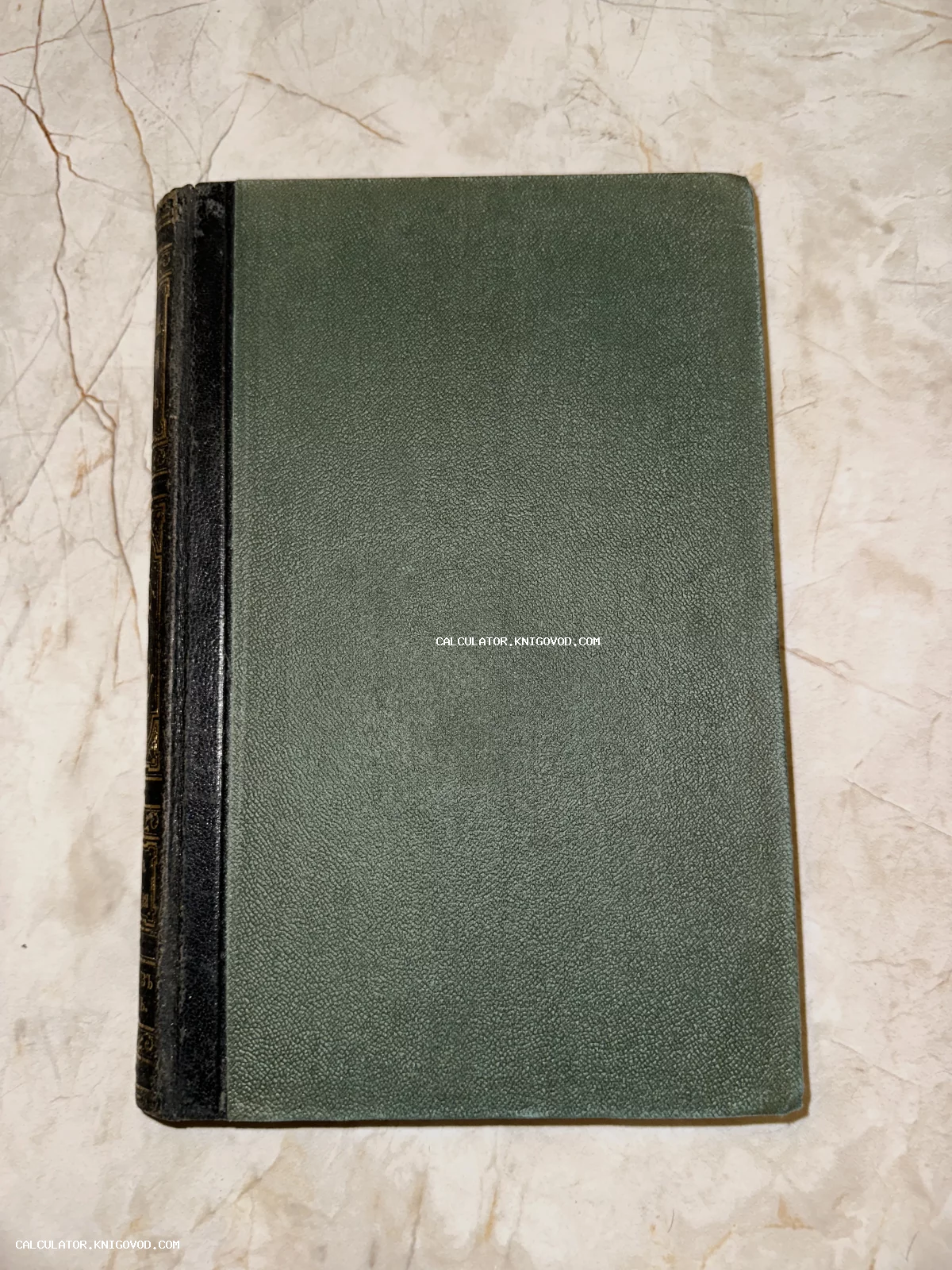 Старинная книга с фактурной зеленой обложкой и черным корешком, украшенным золотым тиснением.