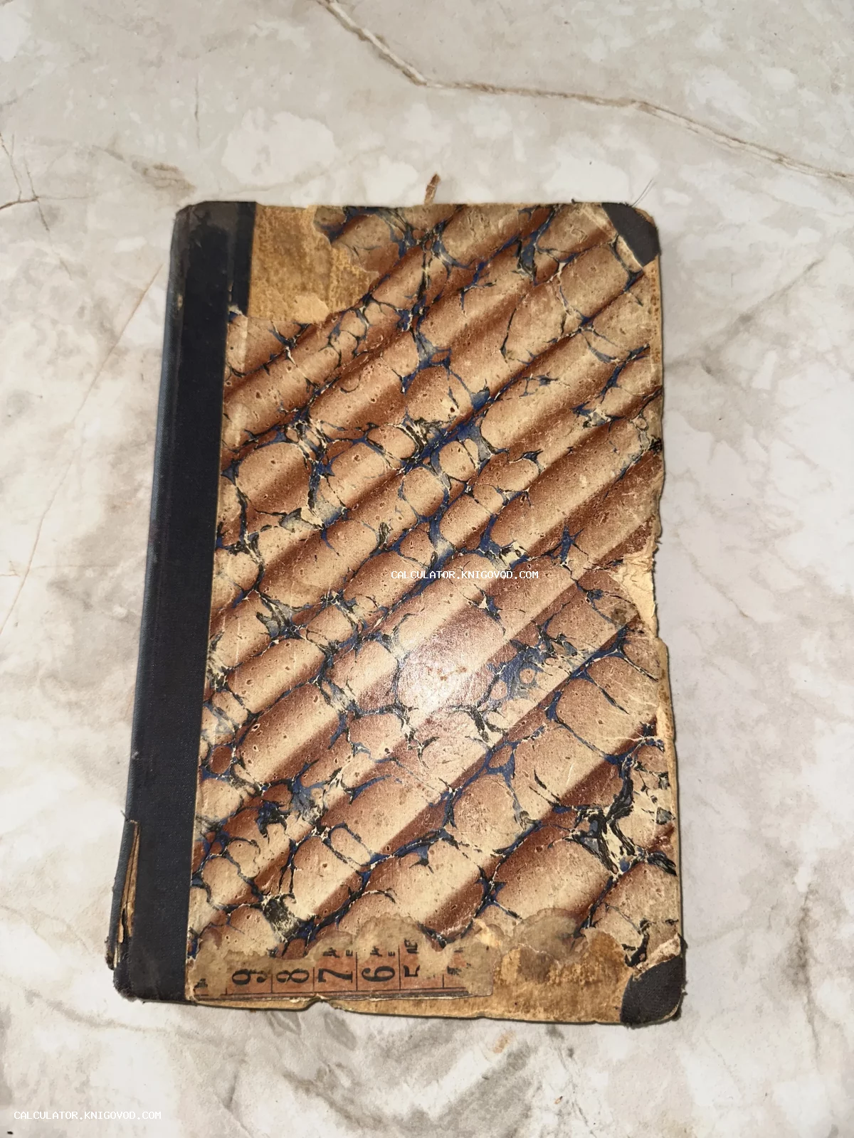 Обложка антикварной книги с мраморным рисунком и черным корешком, имеющая следы значительного износа и старины.