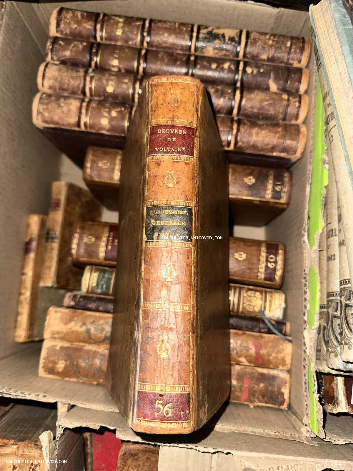 Старинные книги в кожаных переплетах с золотым тиснением в коробке, крупный план корешка тома произведений Вольтера.