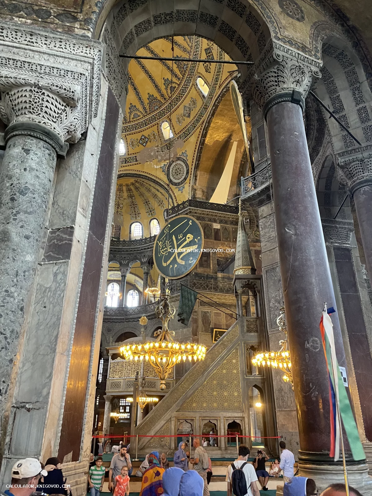 Внутреннее пространство собора Святой Софии в Стамбуле с высокими сводами, массивными колоннами и исламской каллиграфией.