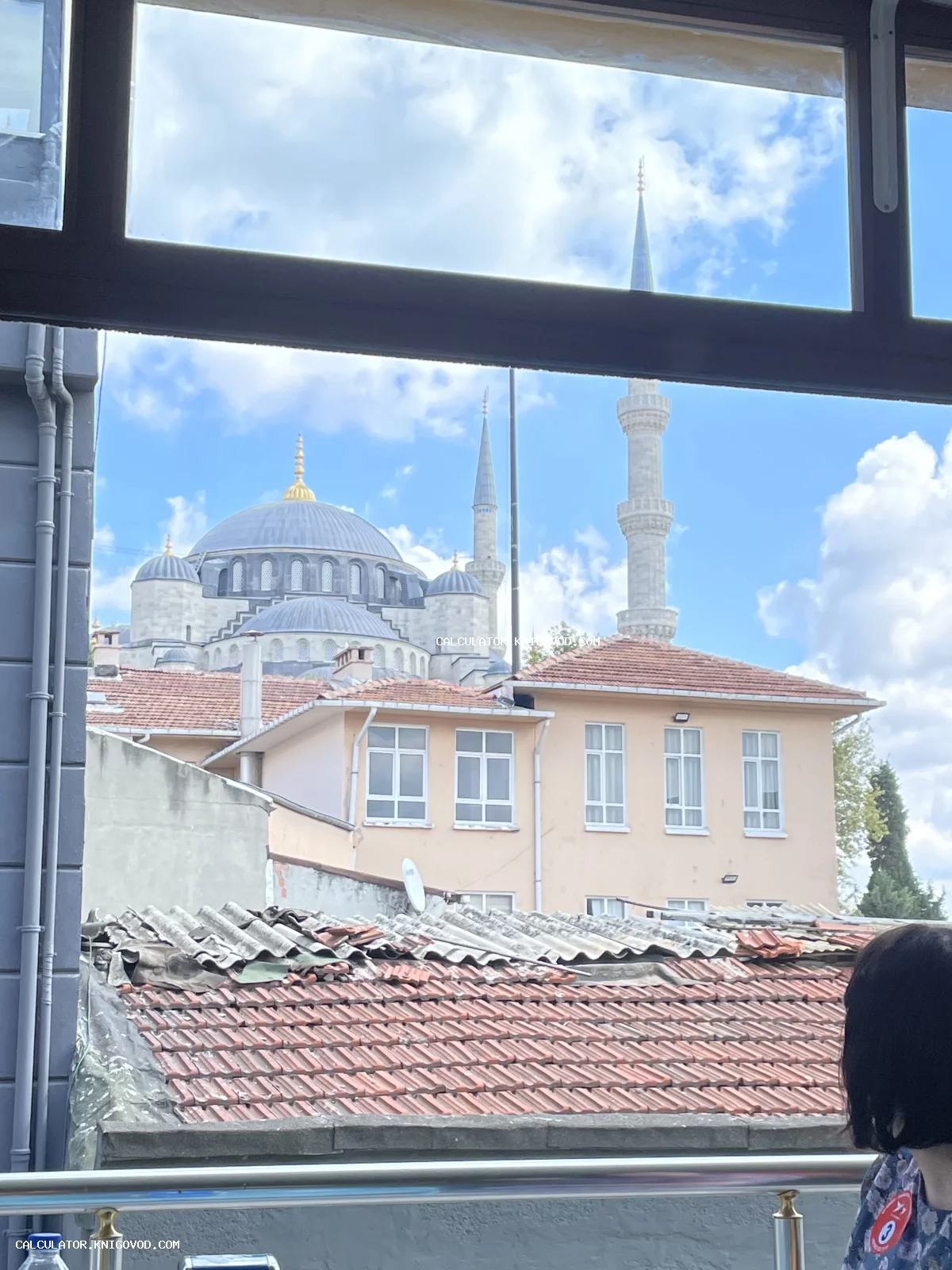 Вид из окна на величественные купола и минареты Голубой мечети в Стамбуле над старыми черепичными крышами.