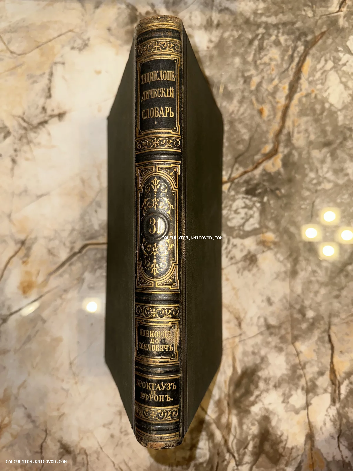 Корешок антикварной книги с золотым тиснением Энциклопедический словарь Брокгауза и Ефрона том 31 на мраморной поверхности