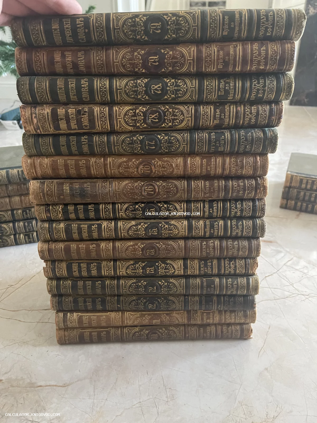 Высокая стопка антикварных книг в кожаных переплетах с золотым тиснением на корешках.