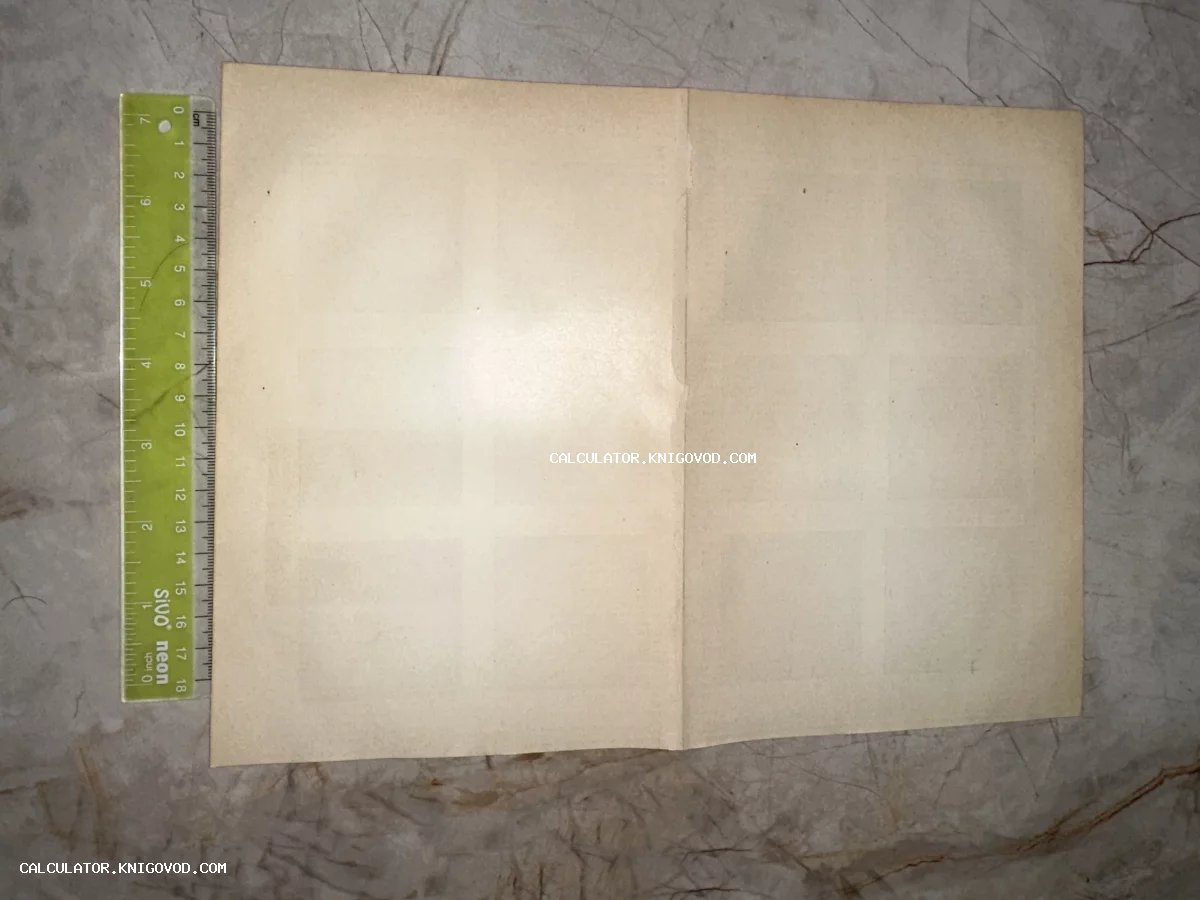 Старинный пожелтевший лист бумаги в развороте, лежащий рядом с зеленой измерительной линейкой на мраморной поверхности.