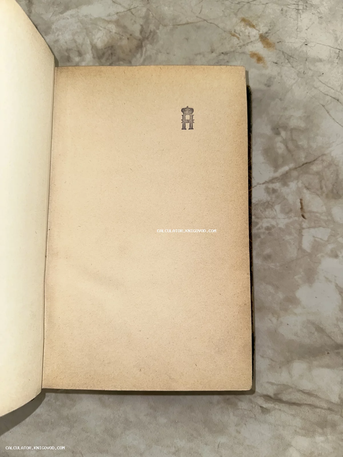 Разворот старинной книги с оттиском коронованной литеры Н на пожелтевшей бумаге.