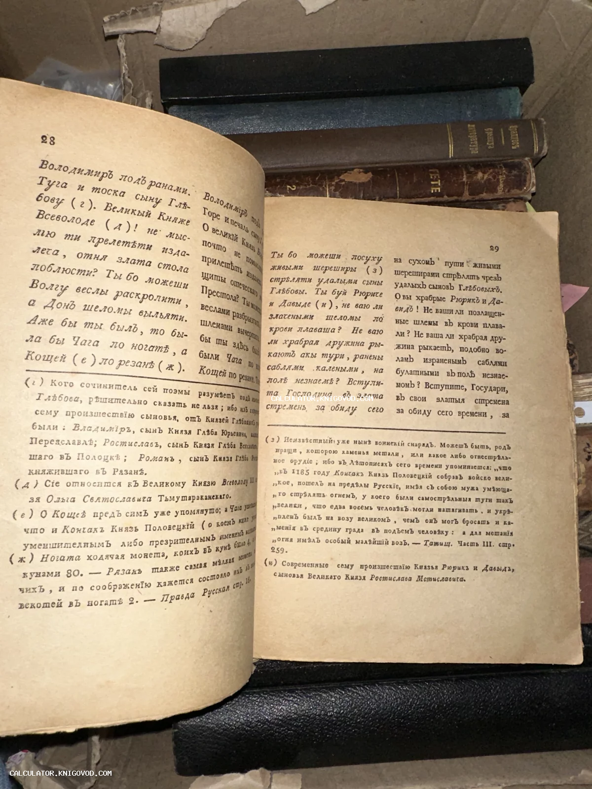 Разворот старинной книги с дореволюционным шрифтом и комментариями к древнерусскому тексту на фоне стопки других книг.