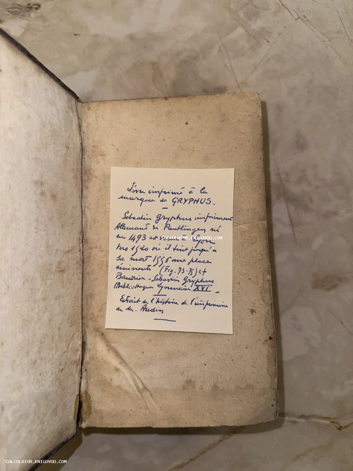 Разворот старинной книги с пожелтевшими страницами и вклеенной рукописной заметкой на французском языке о типографе Себастьяне Грифиусе.