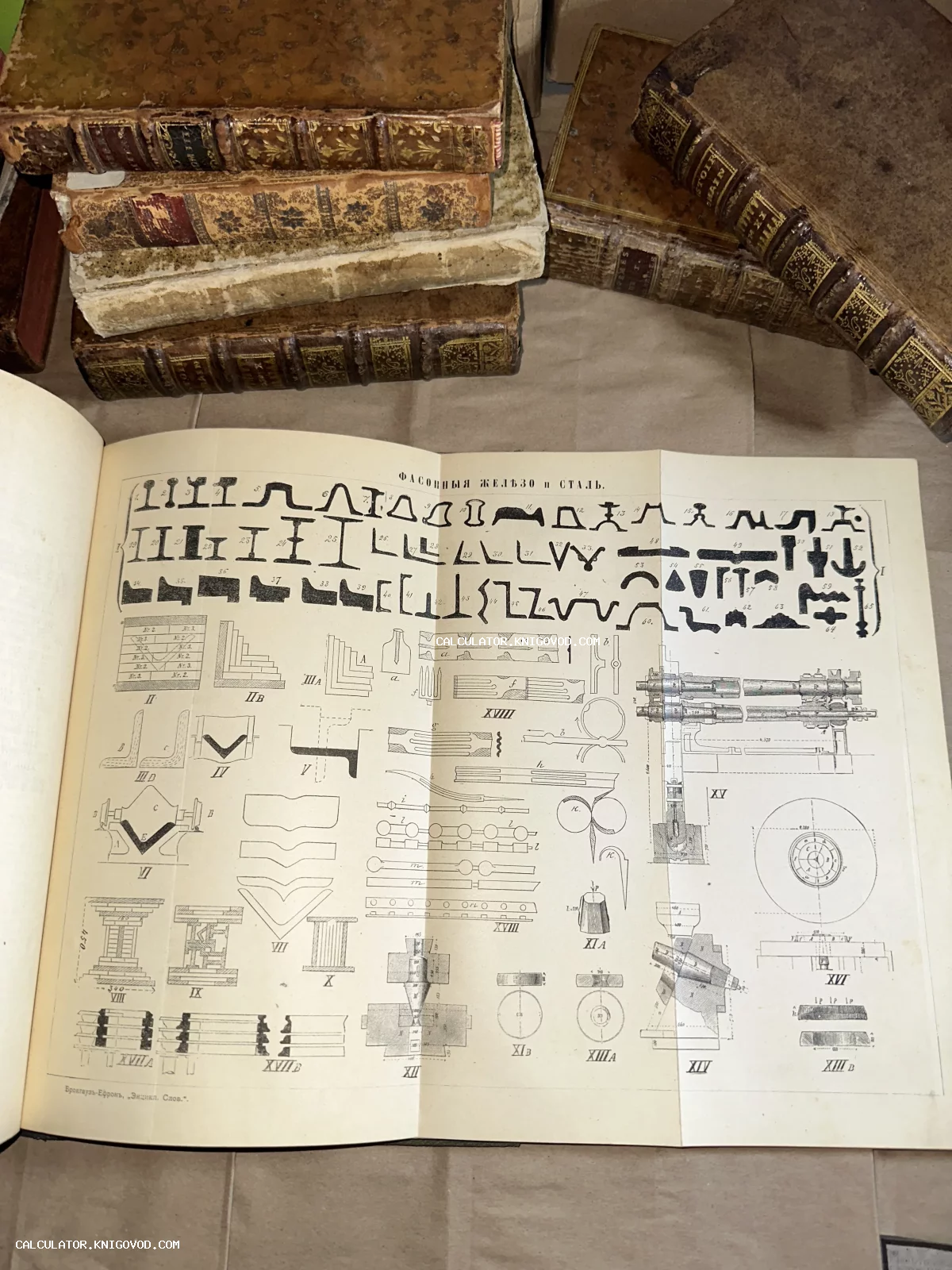 Открытый том энциклопедии Брокгауза и Ефрона с чертежами металлоконструкций на фоне стопки антикварных книг в кожаных переплетах.