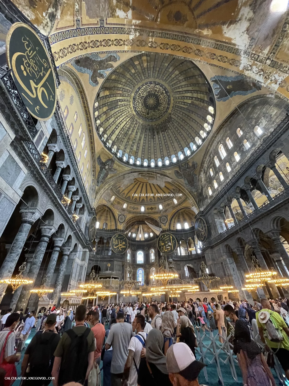 Интерьер собора Святой Софии в Стамбуле с видом на главный купол, исламские медальоны и старинные люстры.