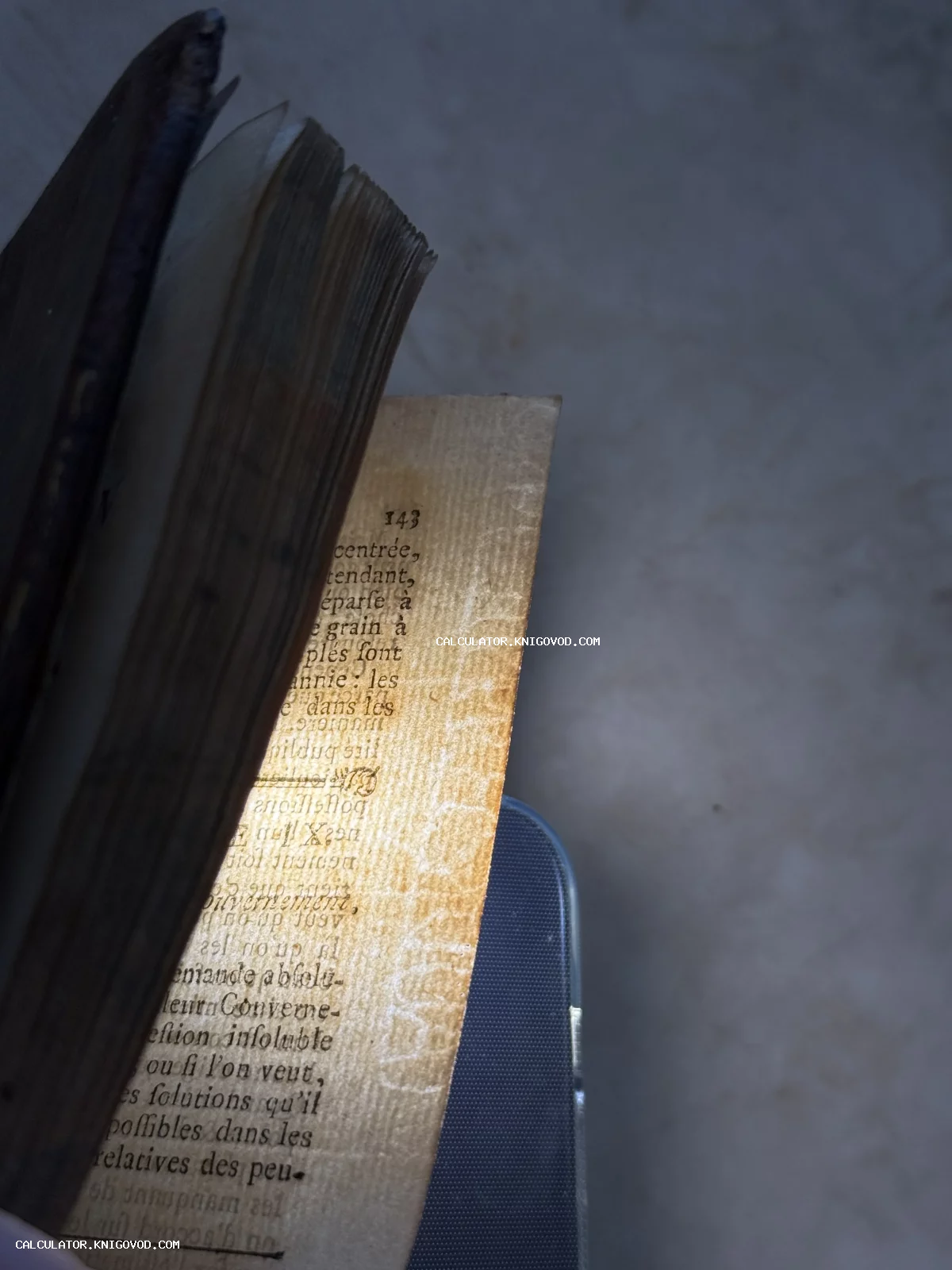 Крупный план раскрытых пожелтевших страниц старинной книги на французском языке с выраженной фактурой бумаги.