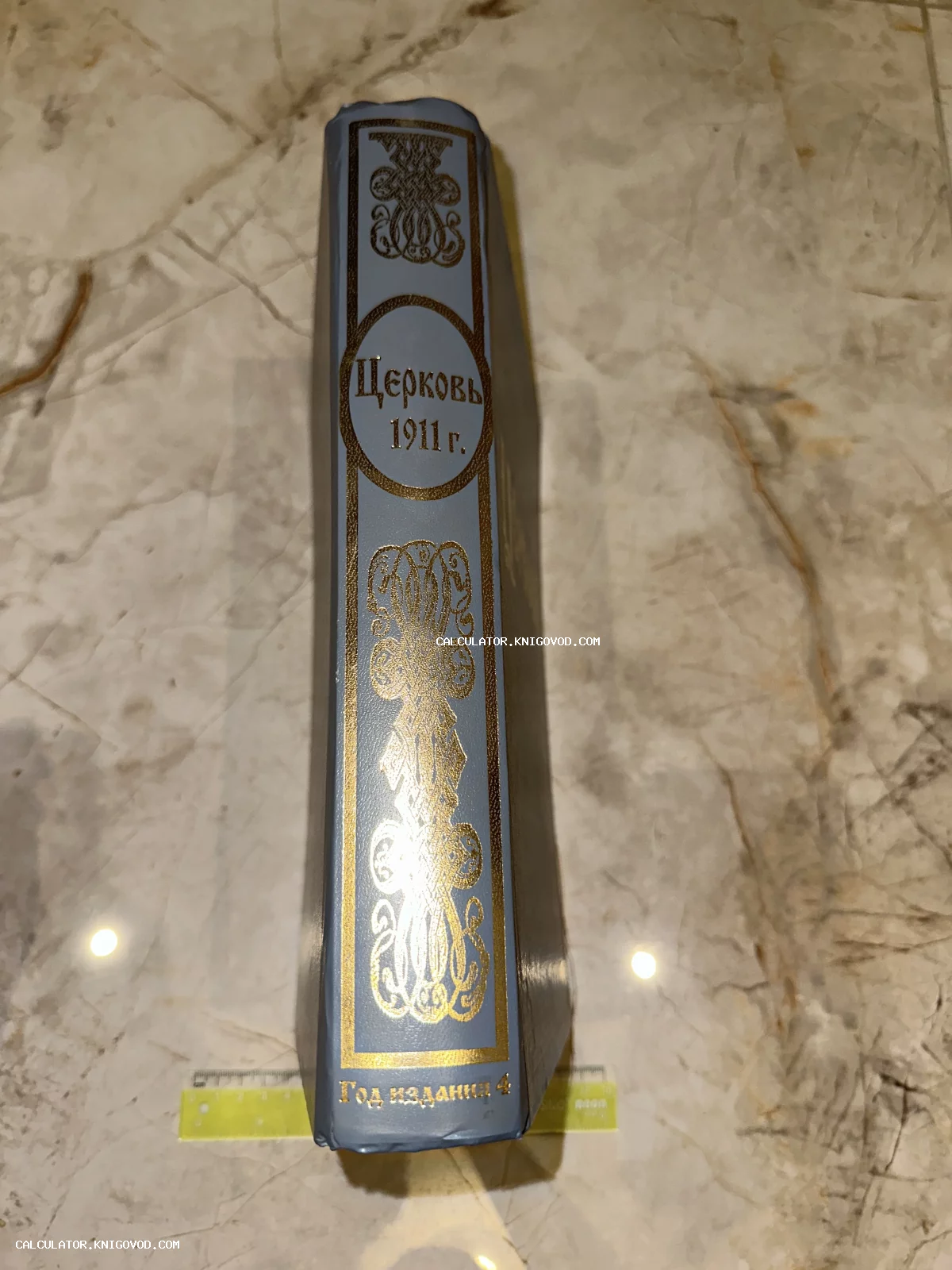 Корешок антикварной книги голубого цвета с богатым золотым тиснением и надписью «Церковь 1911 г.» на мраморном фоне.