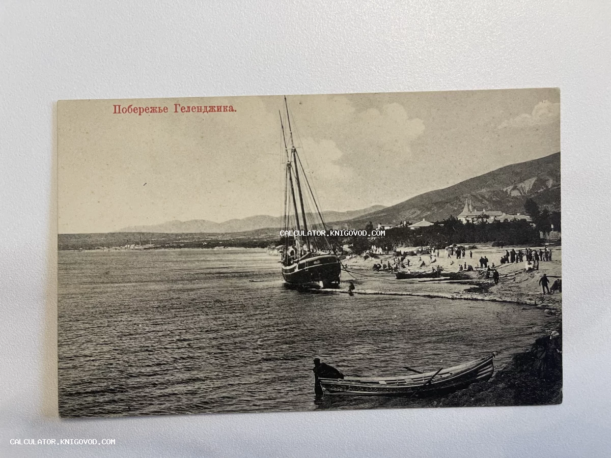 Черно-белая дореволюционная открытка с видом на побережье Геленджика, парусным судном у берега и людьми на пляже.