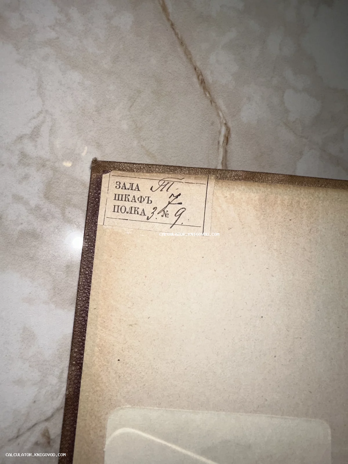 Фрагмент форзаца антикварной книги с наклеенным бумажным ярлыком, содержащим рукописные пометки о расположении тома: зала, шкаф и полка.