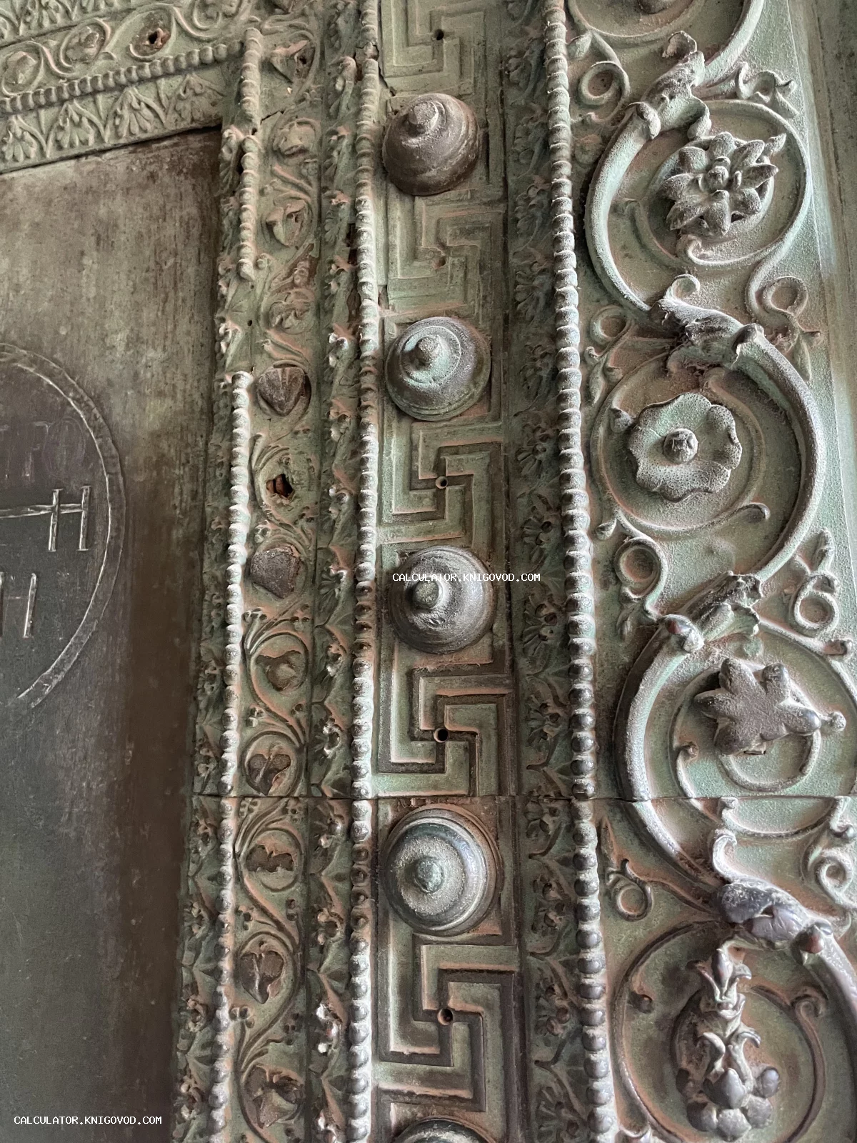 Детальный вид старинной металлической поверхности с чеканным орнаментом меандр, цветочными узорами и окисленной зеленой патиной.