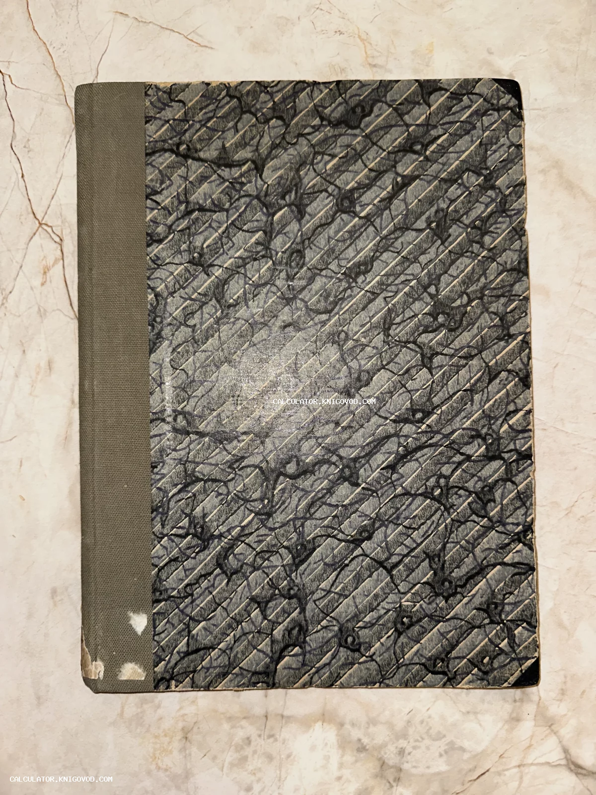 Обложка старинной книги с серым тканевым корешком и диагональным абстрактным орнаментом на мраморной бумаге.