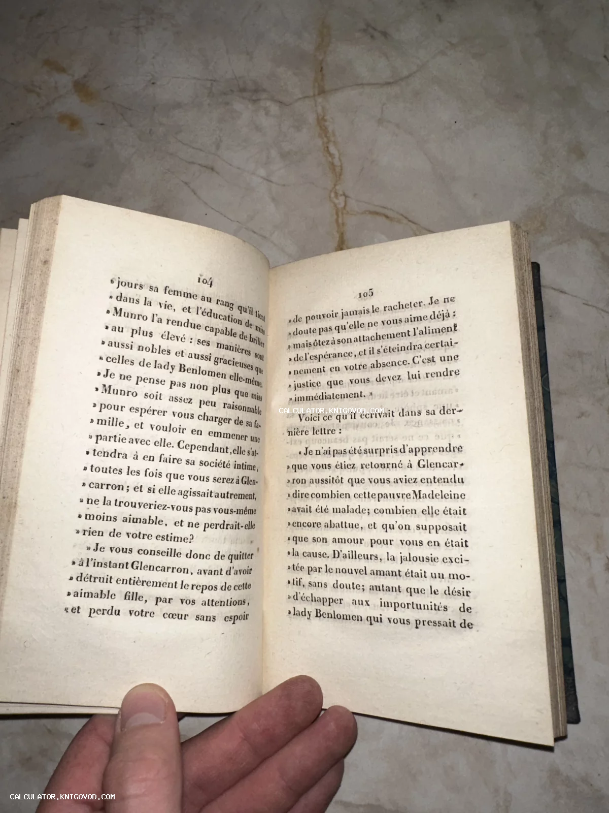 Разворот антикварной книги на французском языке с пожелтевшими страницами на фоне мраморной поверхности.