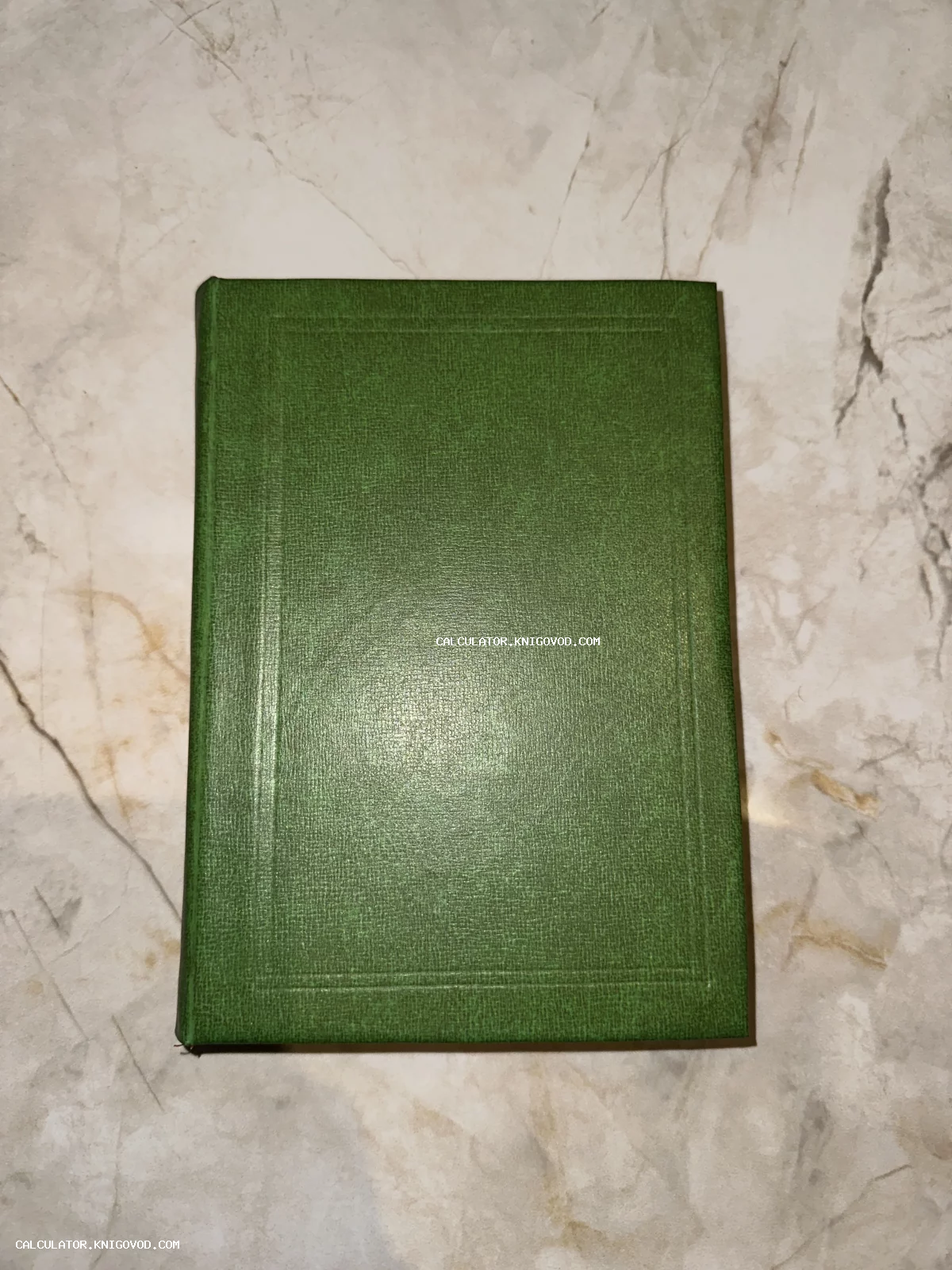 Старинная книга с темно-зеленой обложкой и тиснением на мраморной поверхности