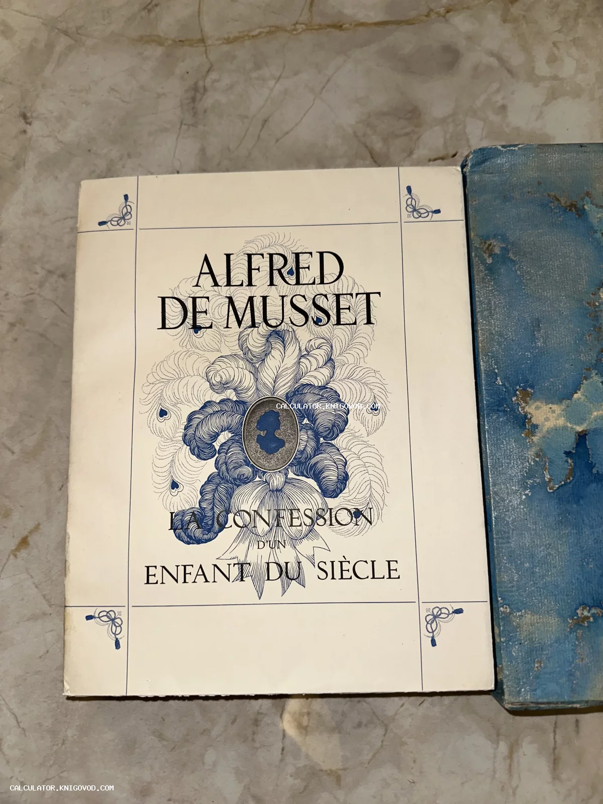 Обложка антикварного издания книги Альфреда де Мюссе 'La Confession d'un Enfant du Siècle' с синим графическим рисунком перьев и медальоном.