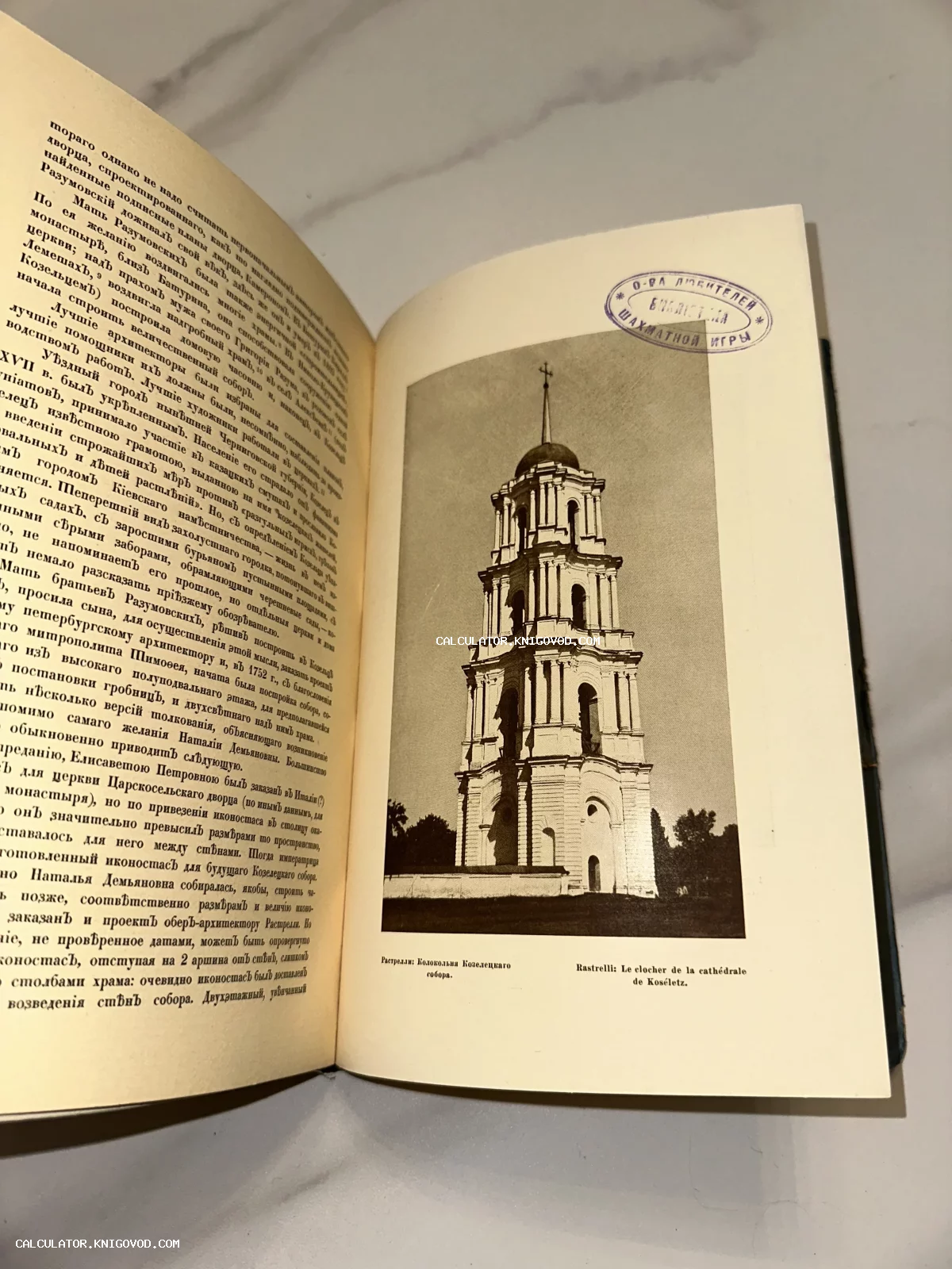 Разворот антикварной книги с текстом на дореволюционном русском языке и фотографией многоярусной колокольни. Справа виден фиолетовый штамп библиотеки Общества любителей шахматной игры.